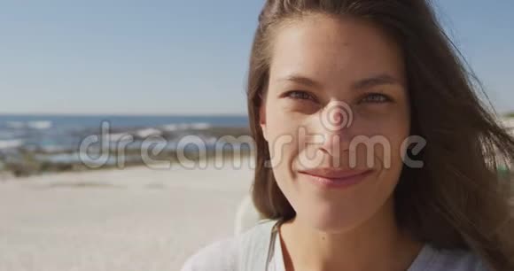 一位年轻女子在海滩上微笑的肖像视频的预览图