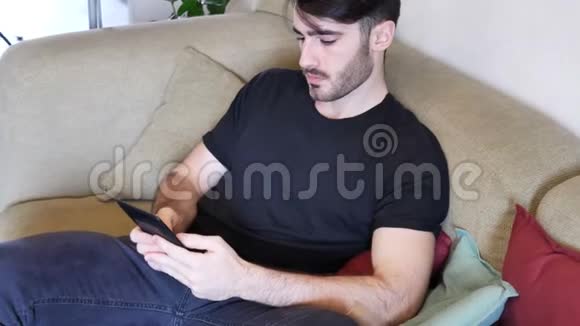 帅哥在沙发上看电子书视频的预览图