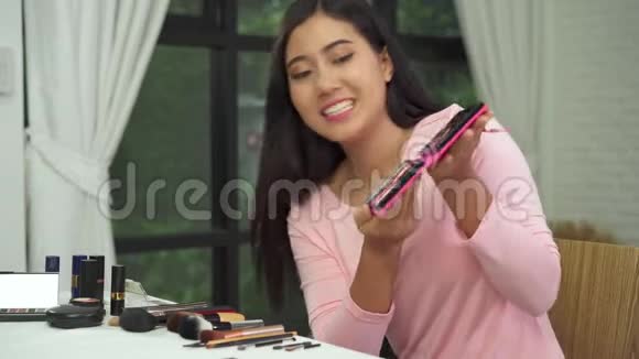 美丽的女人在复习时使用画笔补习通过互联网向社交网络直播视频视频的预览图