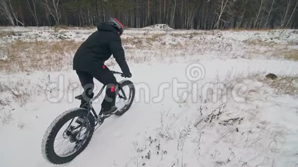 专业的极限运动运动员骑胖自行车在户外骑自行车在冬天的雪田森林人类视频的预览图
