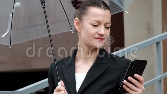 年轻迷人的女人穿着黑色夹克和蓝色牛仔裤在建筑背景下户外摆姿势视频的预览图