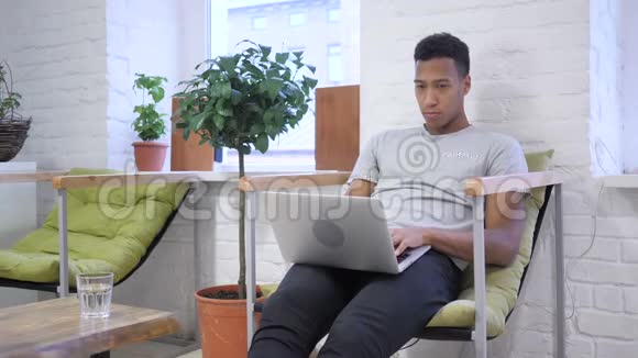 非洲青年打字员在笔记本电脑上工作视频的预览图