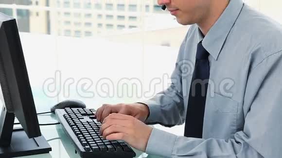 商人在键盘上打字戴着耳机视频的预览图