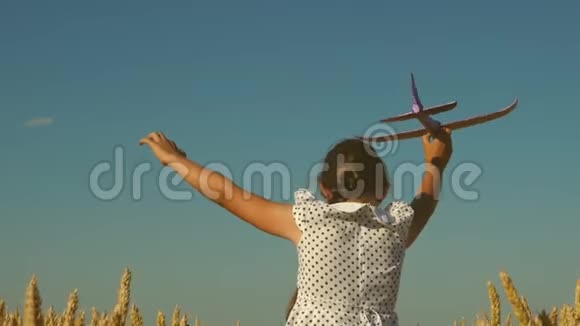 快乐的女孩带着玩具飞机在夕阳下的田野上奔跑孩子们玩玩具飞机少年梦想视频的预览图