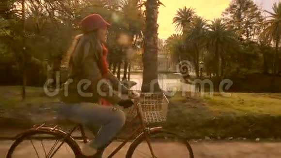 穿着老式时尚自行车的女孩在公园里骑自行车视频的预览图