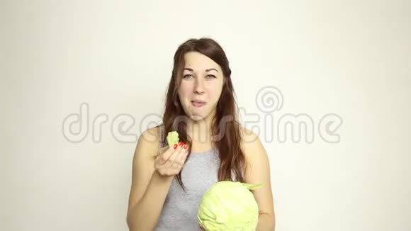 美丽的年轻女人吃蔬菜抱着卷心菜她盯着卷心菜的头健康食品健康食品视频的预览图