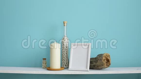 现代客房装饰与相框模型白色架子靠在粉彩绿松石墙上瓶子里有蜡烛和岩石手视频的预览图