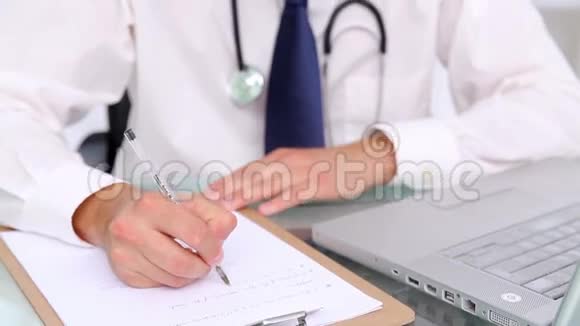 严肃的医生坐在书桌上写字视频的预览图