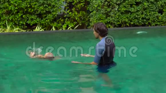 男子游泳教练教小男孩在游泳池游泳视频的预览图