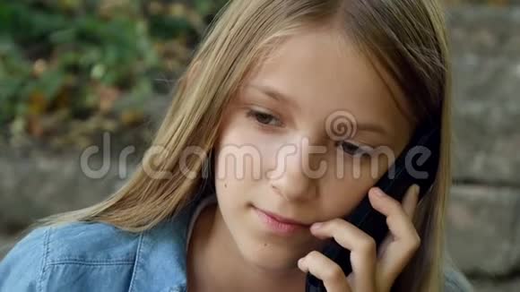 儿童使用智能手机儿童使用智能手机女孩在公园户外玩耍视频的预览图