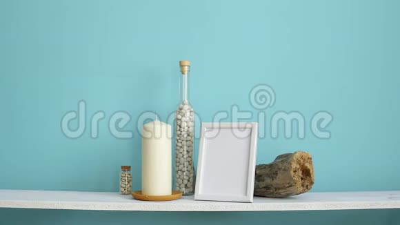 现代客房装饰与相框模型白色架子靠在粉彩绿松石墙上瓶子里有蜡烛和岩石手视频的预览图