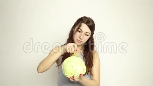 美丽的年轻女人吃蔬菜抱着卷心菜她盯着卷心菜的头健康食品健康食品视频的预览图
