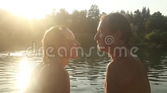 浪漫的情侣在日落时分坐在河边看着对方视频的预览图