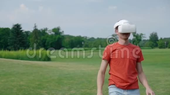 一个男人用VR耳机在公园玩虚拟游戏视频的预览图
