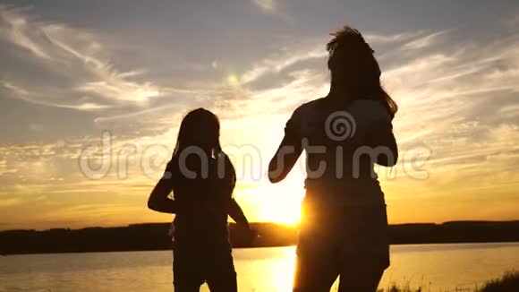 年轻人的女朋友在日落时度假迪斯科湖边的派对孩子们跳舞快乐的女孩在海滩上跳舞视频的预览图