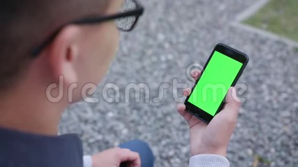 一个使用绿色屏幕手机的年轻人视频的预览图