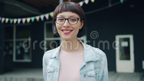 年轻的黑发女人看着相机在户外微笑的慢镜头肖像视频的预览图