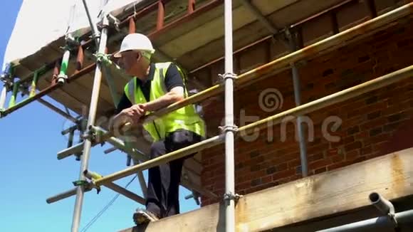 男建筑工人工头建筑工人站在脚手架上视频的预览图