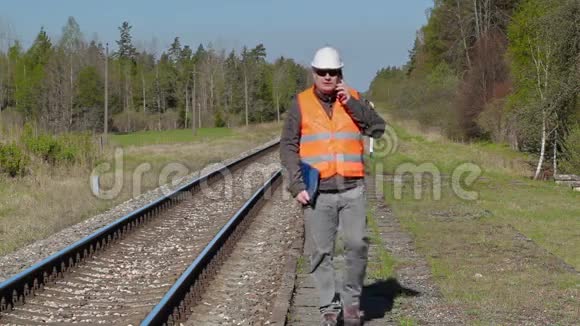 铁路工人在铁路附近的智能手机上行走和交谈视频的预览图