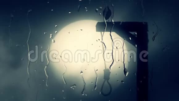 黑色的乌鸦站在绞架上绞索穿过一个带雨滴的玻璃视频的预览图