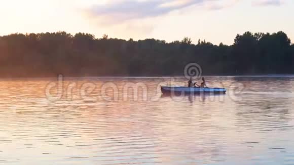 浪漫的金色日落江湖雾情侣小船约会美丽的情人骑马快乐的女人男人视频的预览图