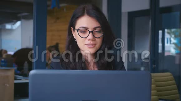 漂亮的年轻女商人在现代办公室里用笔记本电脑工作视频的预览图