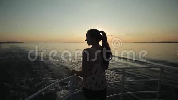 日落时分在船上摆姿势的美丽女孩的侧景视频的预览图