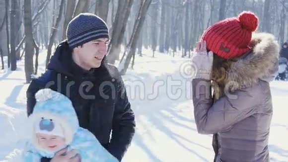 父亲和母亲在公园里散步孩子在冬天慢动作视频的预览图