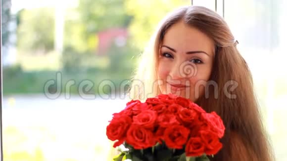 一个年轻美丽的女人带着一束红色玫瑰花的肖像视频的预览图
