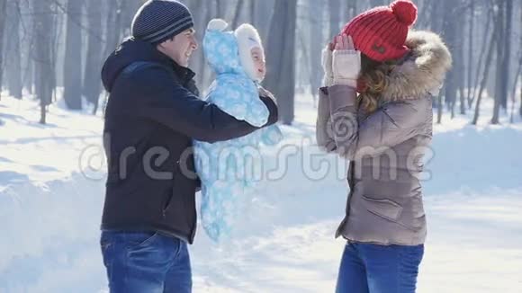 父亲和母亲在公园里散步孩子在冬天慢动作视频的预览图