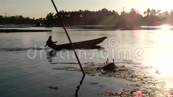 男孩靠船在湖里当渔夫谋生剪影视频的预览图