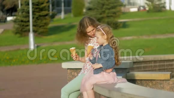 妈妈和女儿在公园里吃冰淇淋母亲和孩子轻松愉快的家庭视频的预览图