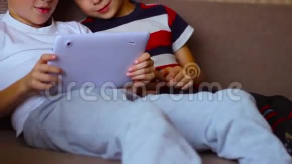 两个男孩在平板电脑和笔记本电脑上玩视频的预览图