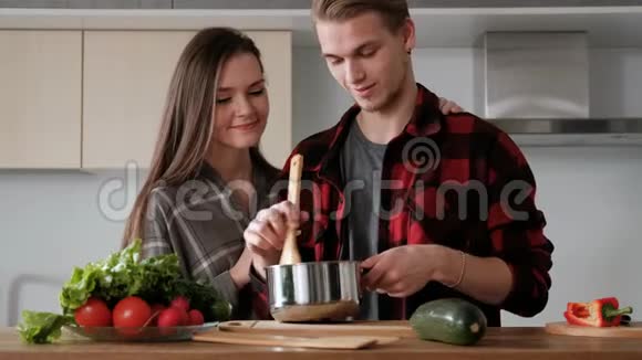 年轻漂亮的一对穿格子衬衫的夫妇正在家厨房做饭视频的预览图