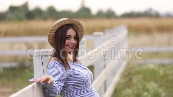 大自然中的孕妇试穿针织帽子农场附近的田野和白色沼泽的背景视频的预览图