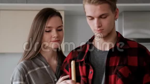 年轻漂亮的一对穿格子衬衫的夫妇正在家厨房做饭视频的预览图