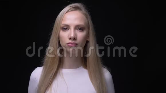 年轻漂亮的金发女性的特写镜头看着背景与黑色隔离的相机视频的预览图