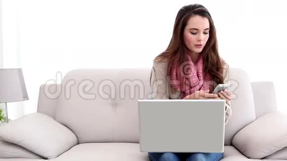 穿着笔记本电脑和打电话的漂亮黑发女人视频的预览图