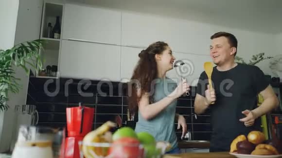 年轻快乐的一对夫妇在家里的厨房里做早餐时一边跳舞一边唱歌玩得很开心视频的预览图