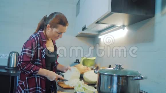 厨房里的女人准备一顿饭的概念厨房里的女孩用刀切卷心菜烹饪素食视频的预览图