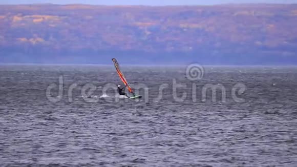 一个男运动员对风帆运动很感兴趣他在大湖上的帆板上移动视频的预览图
