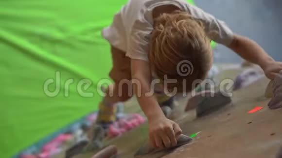 一个小男孩正在一个巨石攀爬体育馆里爬墙视频的预览图