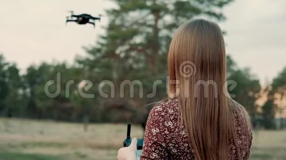 日落时分一个年轻快乐的女孩带着遥控器控制着四架直升机在野外飞行视频的预览图
