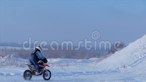 摩托车儿童自行车骑手在雪地摩托车越野赛道雪上的骑士骑自行车的摩托车骑手冬季骑摩托车视频的预览图