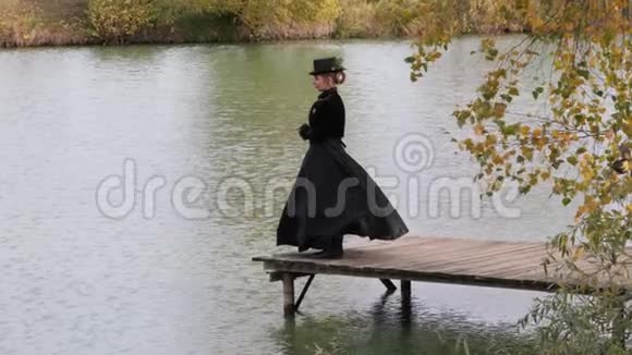 秋天在水的背景上穿黑色裙子的女孩视频的预览图