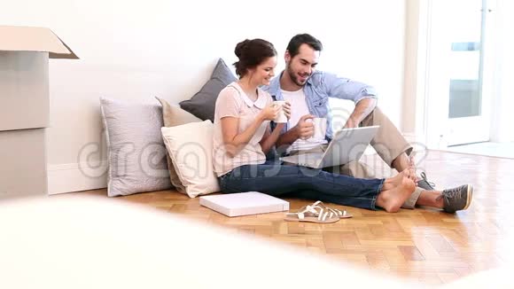 有魅力的情侣在地板上用笔记本电脑视频的预览图