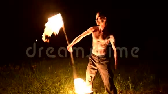 低调年轻男性长头发裸露的躯干在黑色的夜间视频中旋转燃烧的火炬视频的预览图