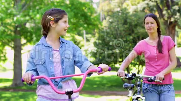 可爱的母亲和女儿一起在公园骑自行车视频的预览图