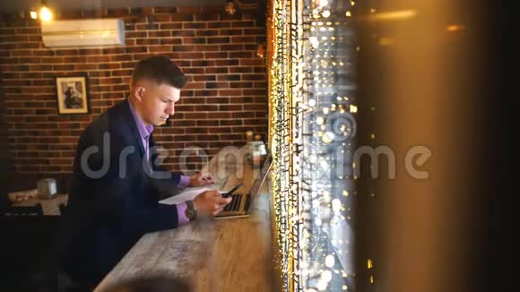一个年轻的商人在一家有笔记本电脑的咖啡馆工作视频的预览图