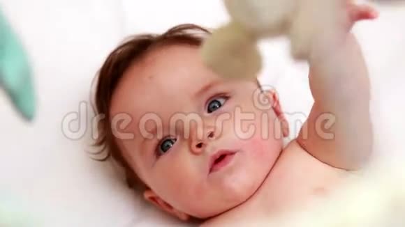 可爱的宝宝在婴儿床上玩手机视频的预览图